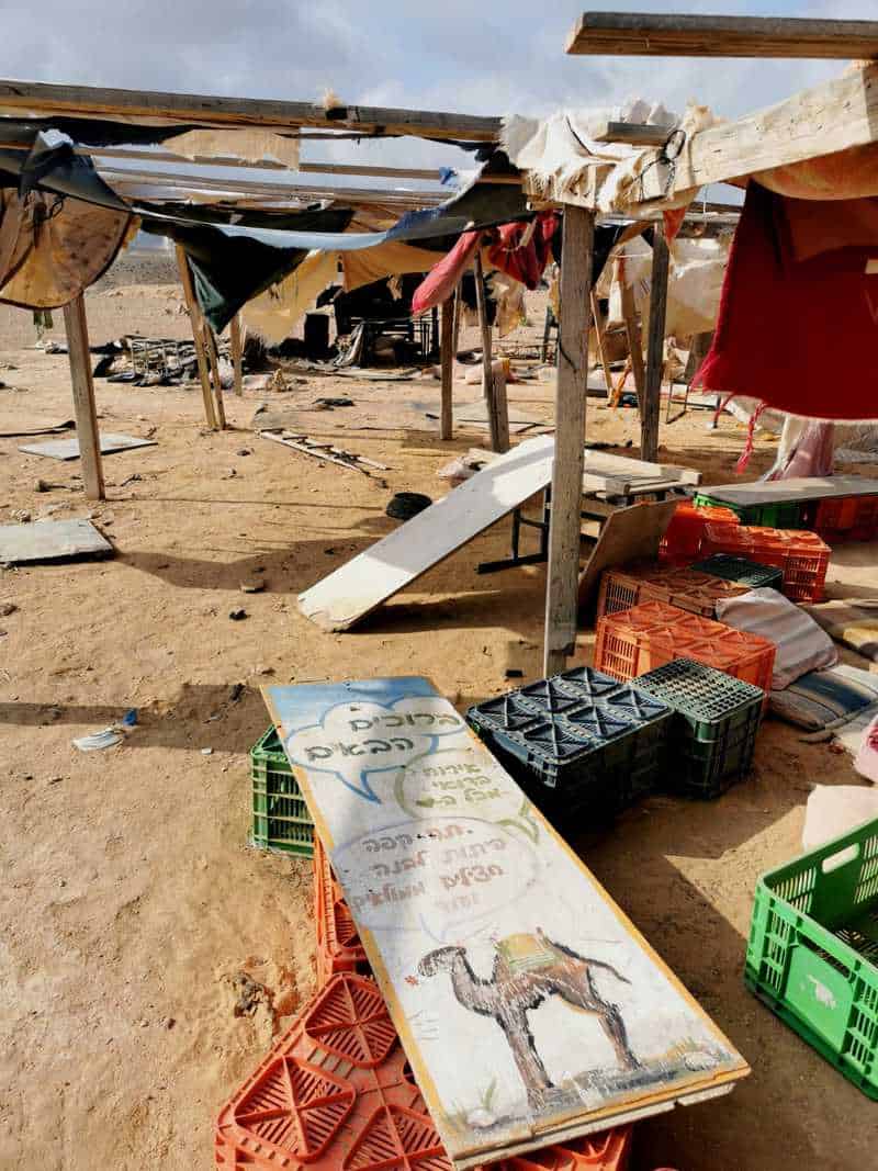 שלט תלוש ליד אוהל נטוש עם קרעי בדים ושברי ארגזים העיד על ימים טובים יותר והזמין את המטיילים לאירוח