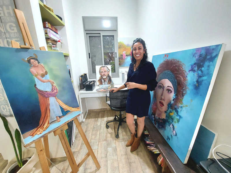 גלית דהרי עם כמה מהציורים שלה | צילום: רותם בר כהן