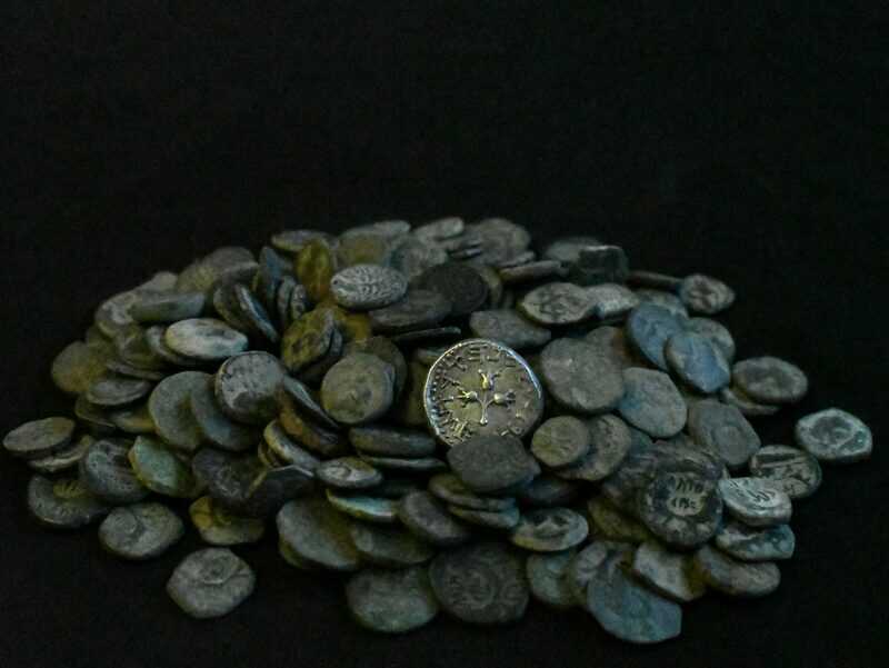 חלק מהמטבעות שנתפסו בבית סוחר העתיקות הבלתי חוקי. במרכז התמונה שקל כסף קדום.
