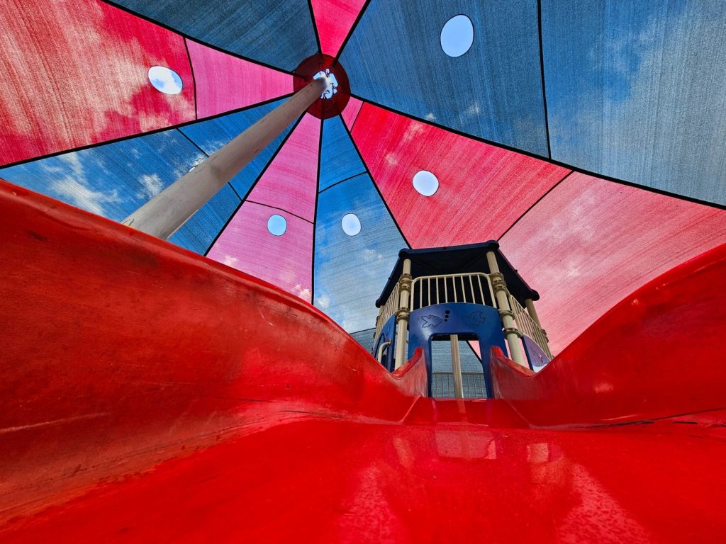 זיו צדוק. בצילום של זיו ניכרת ההשקעה. כדי לצלם את התמונה מהזווית הזאת יש צורך להתכופף ולשכב ממש על המגלשה האדומה. כדי להתמקד בצבע אדום ולא לפספס גם את הרקע מאחור זיו השתמש בעדשה אולטרה רחבה. בצילום מזווית נמוכה נוצר לנו כאן תמונה מלאת צבע, שמדגימה בצורה טובה איך צילום טוב יכול להפוך את הרגיל - לבלתי רגיל