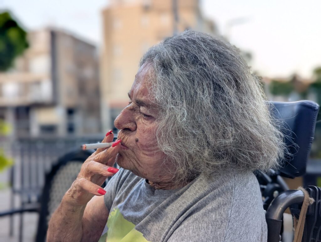 דידי משה. דידי צילמה תמונה שכולה תנועה ואופי, בה תווי הפנים של המצולמת מודגשים על ידי “יניקת” הסיגריה. זווית הצילום מקרוב מכניסה אותנו פנימה לתוך החיים של המצולמת, יחד עם ריחוק מסויים שנובע מהצילום מצד הפרופיל. איכות הצילום מודגשת באמצעות מצב פורטרט, שהוא אחת האפשרויות הטובות ביותר למיטוב התמונה בסמארטפון.